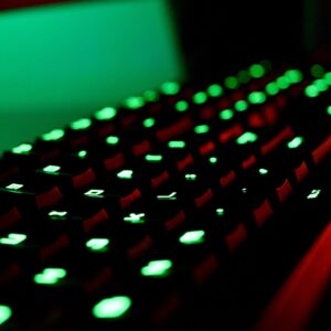 Close-up of a backlit gaming keyboard with vibrant green LED lights creating a glowing effect.